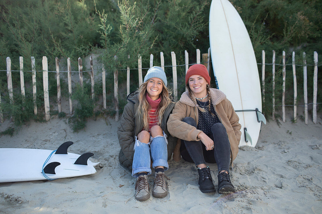 Happy young female surfers with surfboards on beach path
