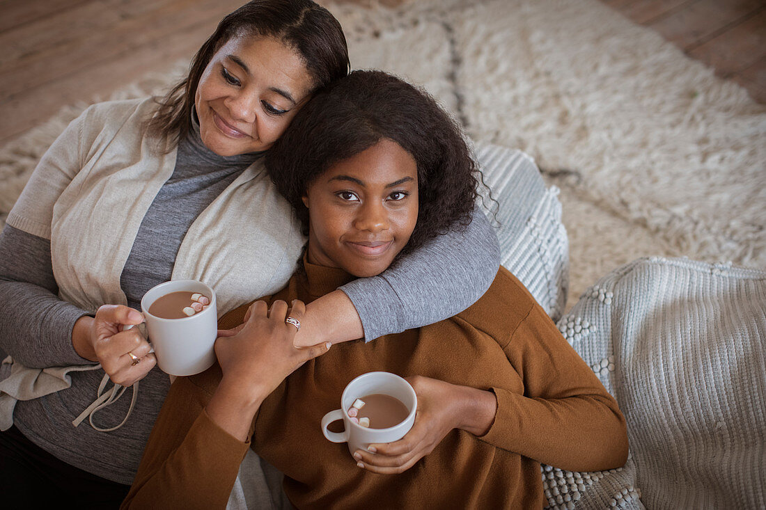 Affectionate mother and daughter cuddling with hot cocoa