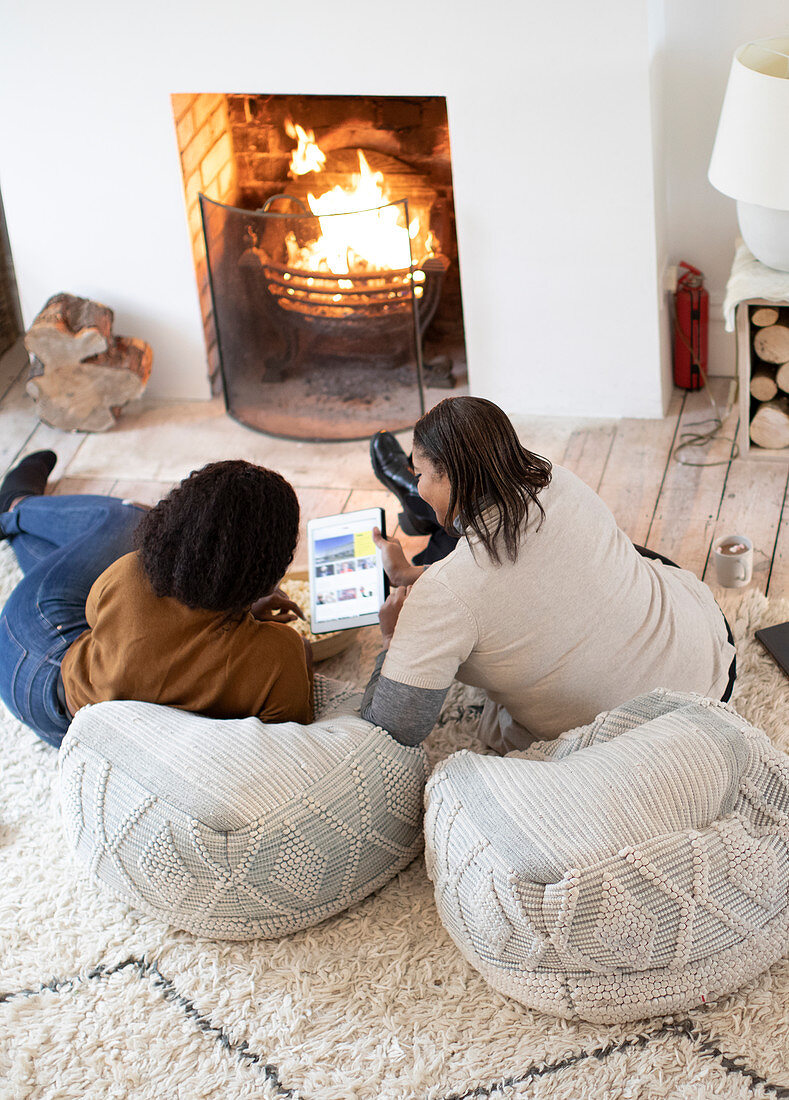 Mother and daughter using digital tablet by fireplace