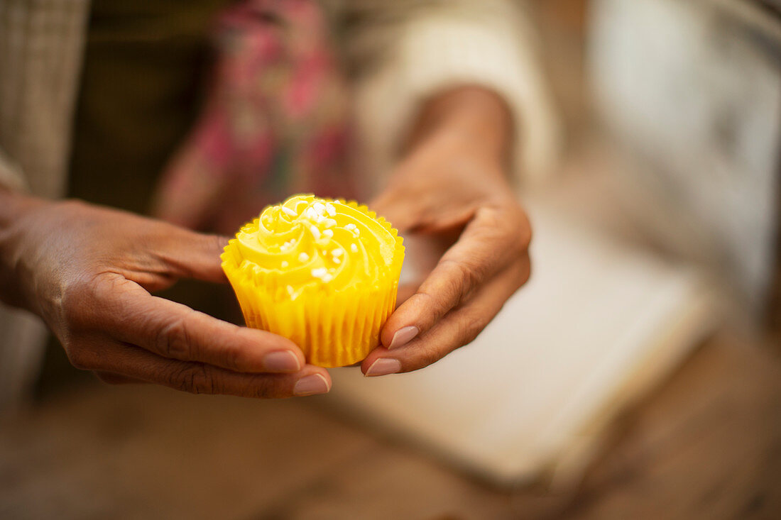 Woman holding bright yellow lemon cupcake