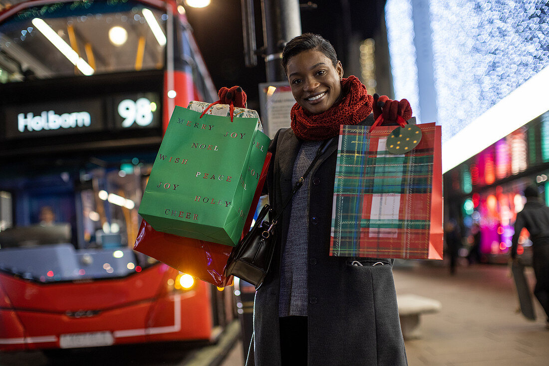 Happy young woman with Christmas gifts in city at night