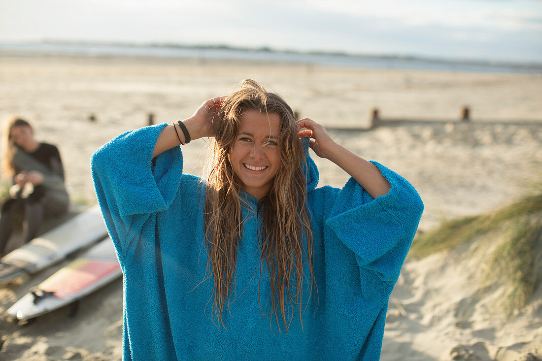 Happy young female surfer with wet hair on sunny beach