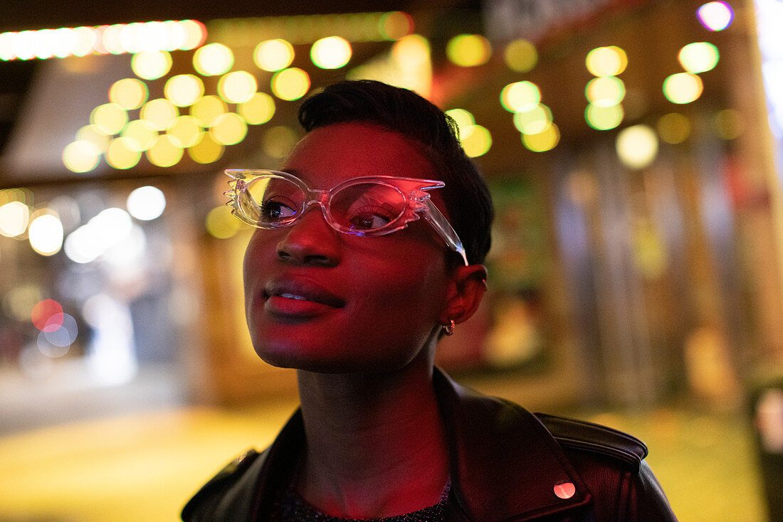 Young woman in funky glasses in city at night