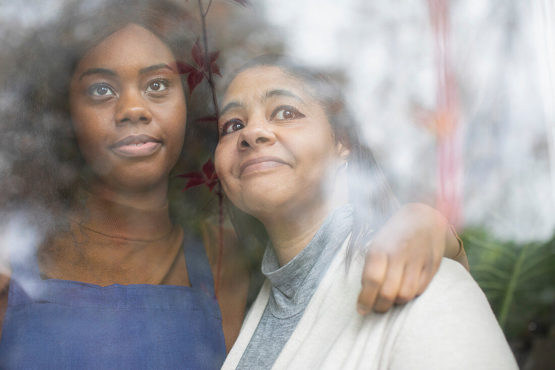 Affectionate mother and daughter looking out window