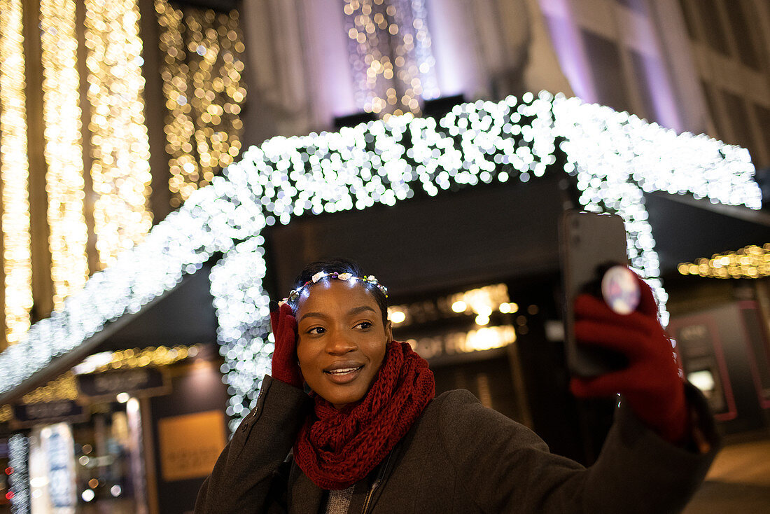 Young woman in Christmas light headband taking selfie