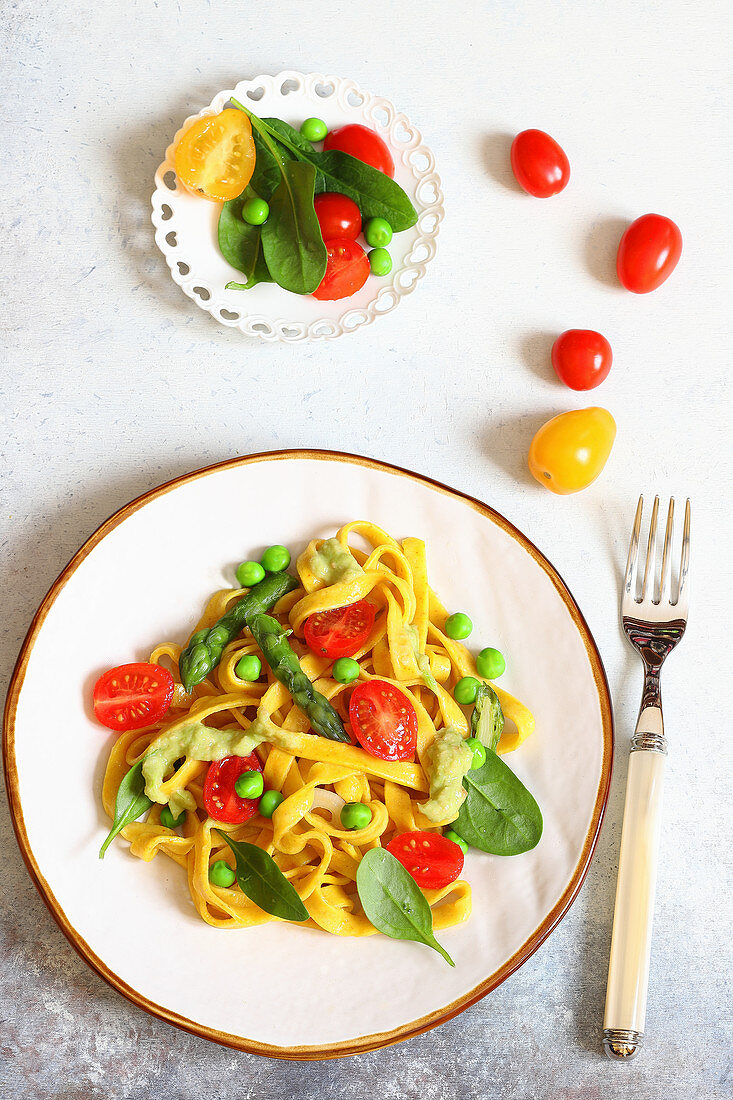 Saffron tagliatelle with green asparagus, peas and tomatoes