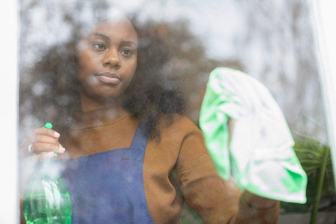 Woman cleaning window with glass cleaner and towel