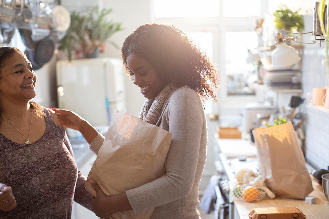 Mother and daughter unloading groceries in kitchen