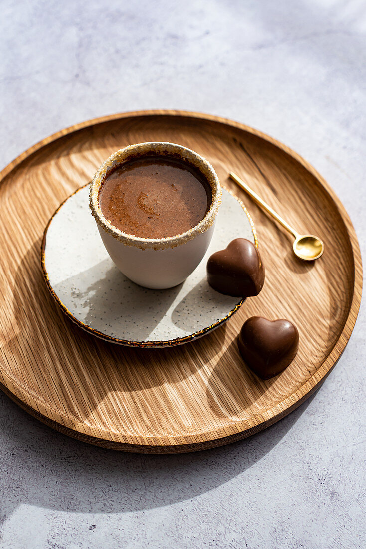 Tasse heiße Schokolade mit Zuckerrand und Pralinen in Herzform