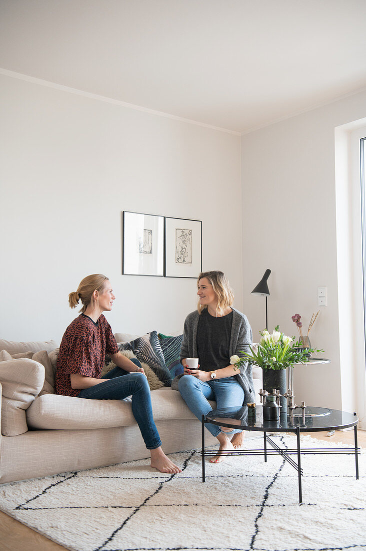 Two friends sitting on the sofa with coffee