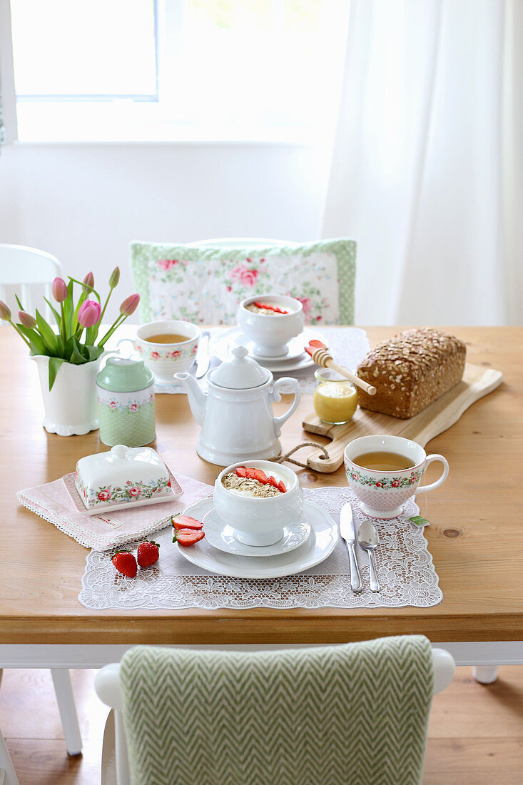 Gedeckter Frühstückstisch mit Müsli, Tee, Kastenbrot und Tulpen