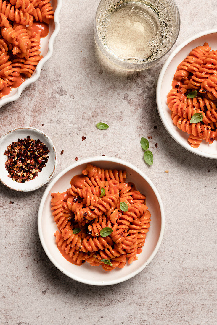 Bowls of roasted red pepper pasta with a glass of white wine