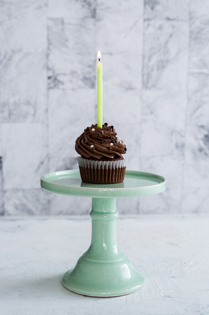 Geburtstags-Schokoladen-Cupcake mit einer brennenden Kerze