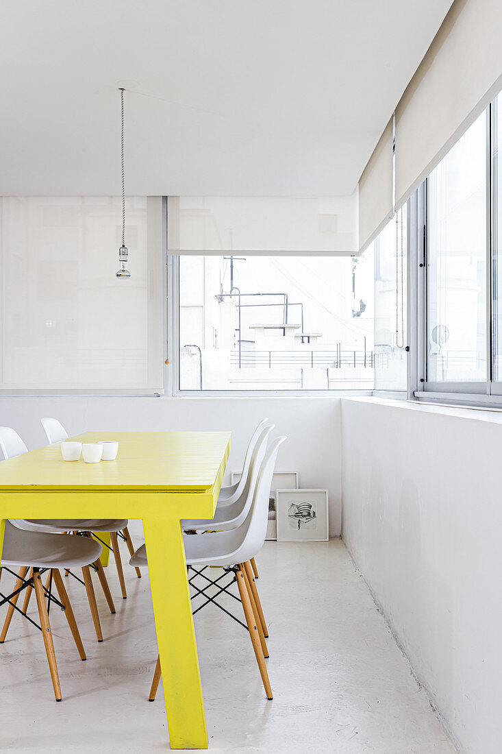 Yellow lacquered dining table and classic white chairs in a bright room