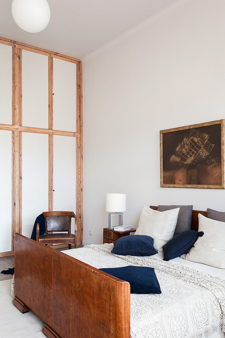 Double bed with wooden footboard in a high-ceilinged bedroom