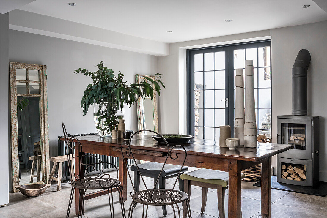 Metal chairs at the wooden table in the rustic dining room with stove