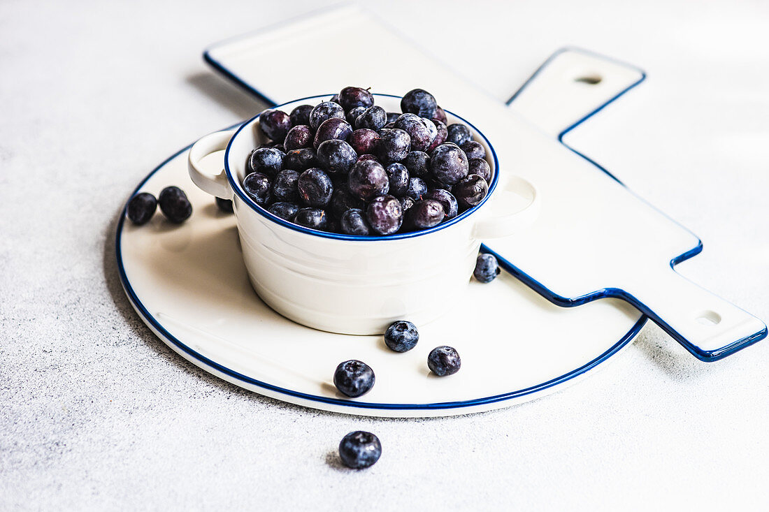 Raw organic blueberry in white bowl on minimalistic concrete background