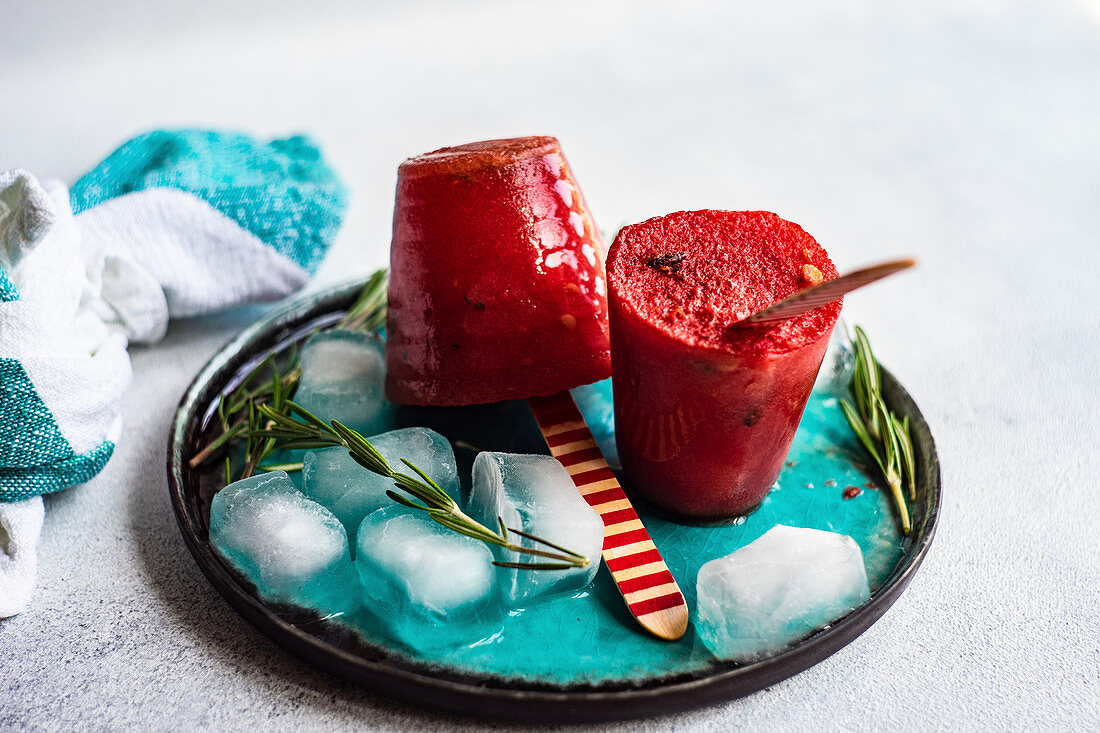 Summer dessert with organic watermelon popsicles served on plate with ice and rosemary