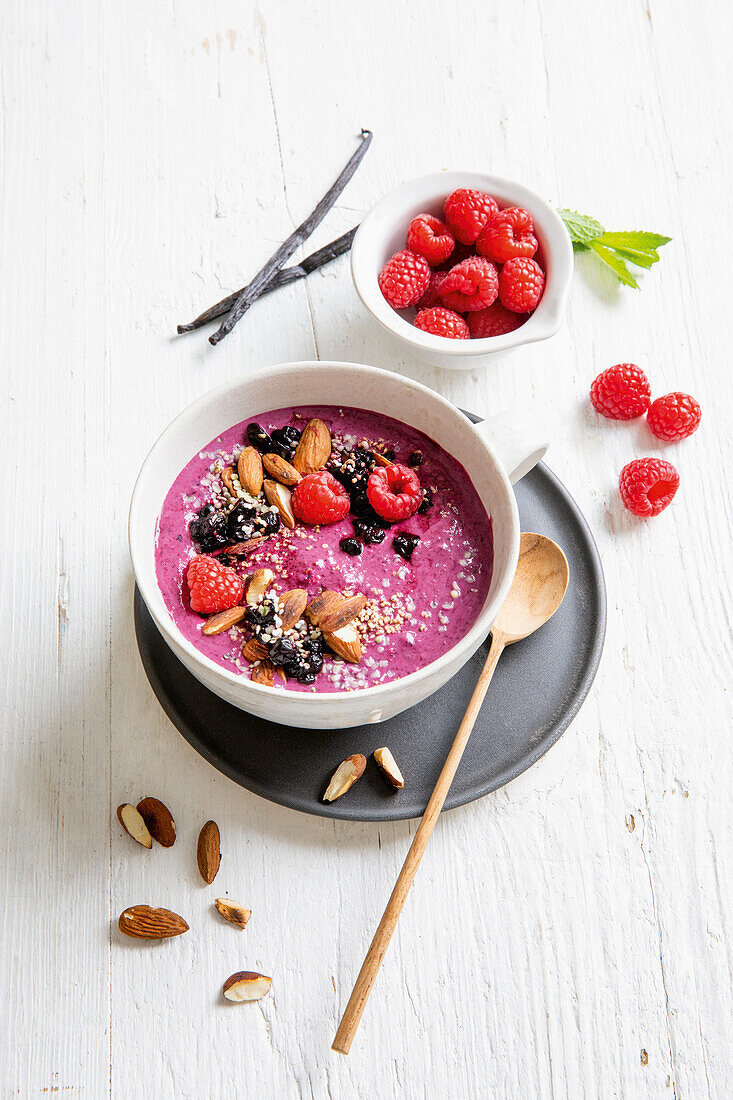 Pink smoothie bowl with raspberries and almonds