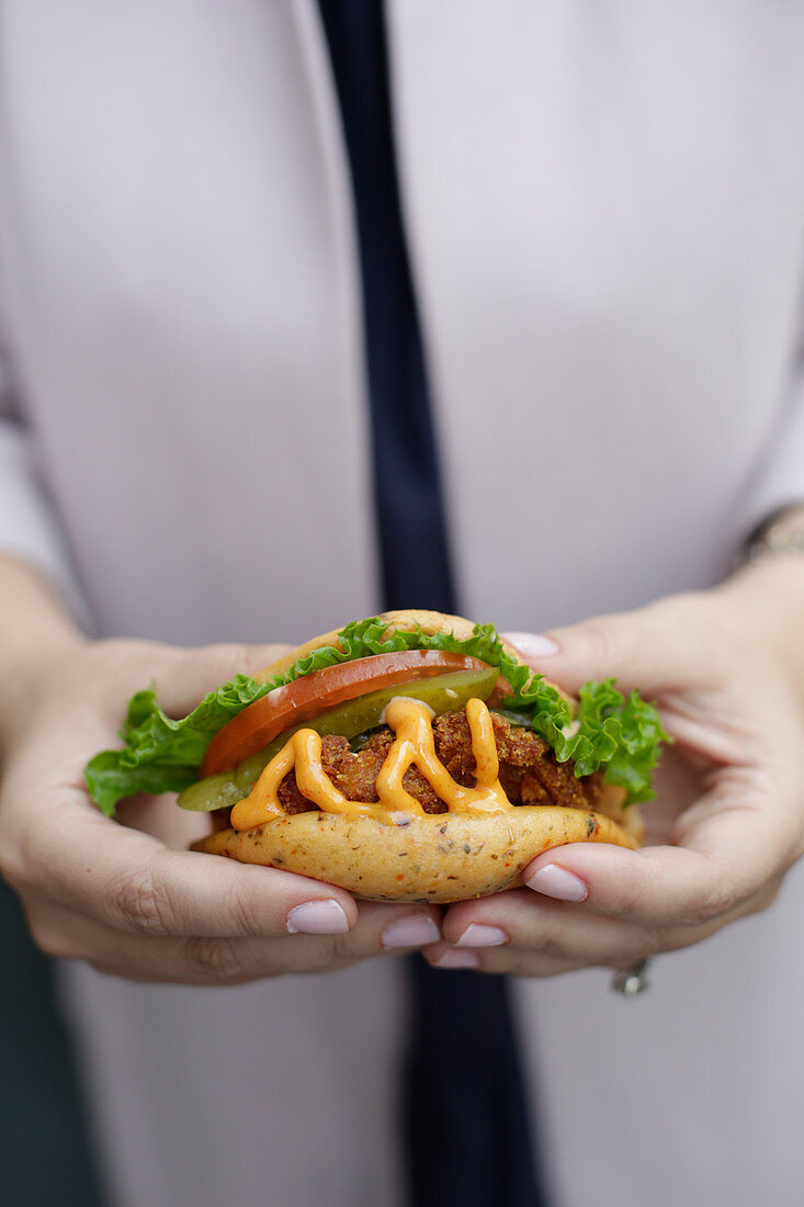 Frau hält Sandwich mit Hähnchenfleisch in den Händen