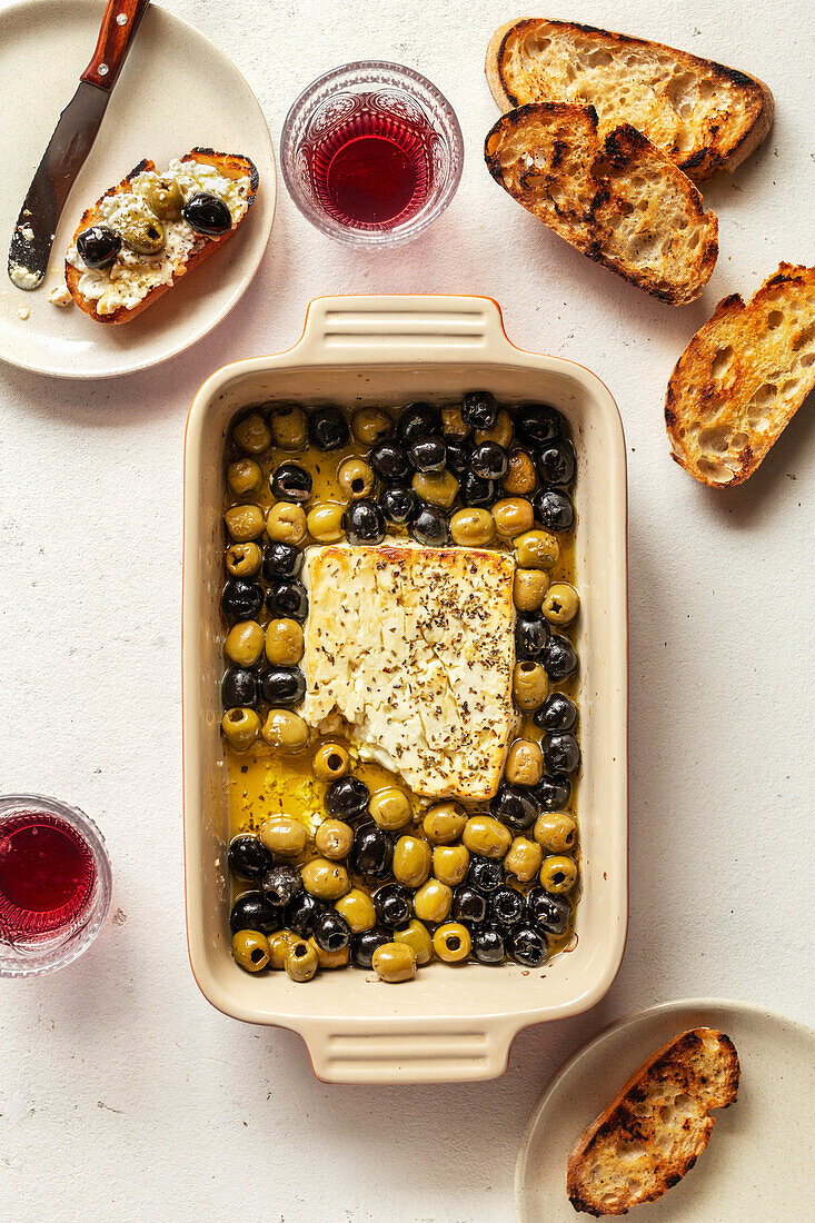 Baked feta cheese with olives in a baking dish