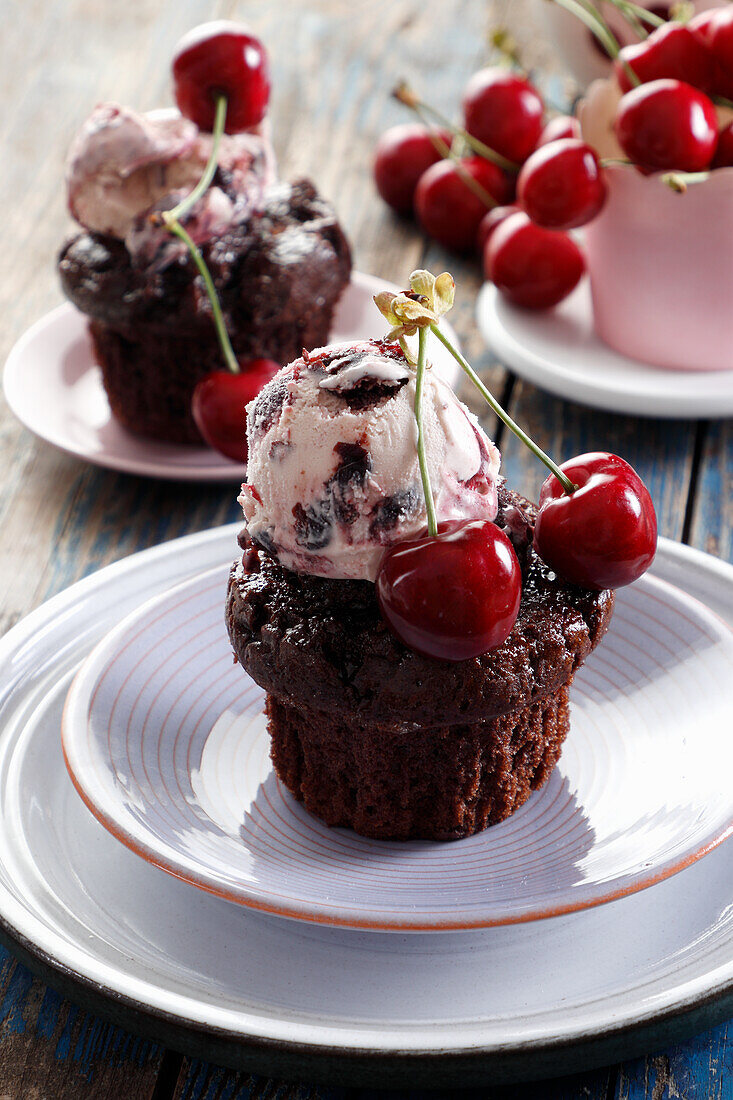 Chocolate muffin served with a scoop of ice cream and cherries