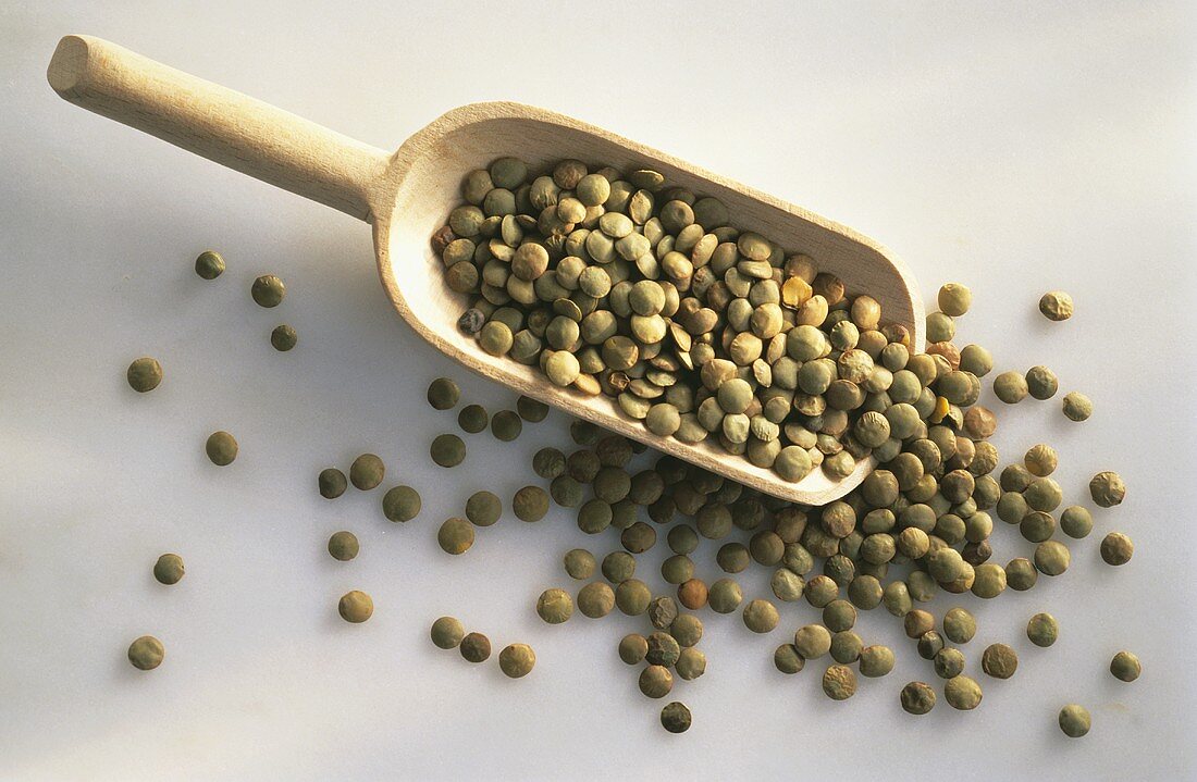 Green lentils on wooden scoop