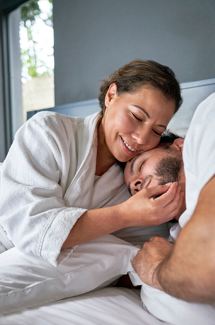 Happy affectionate couple cuddling on bed