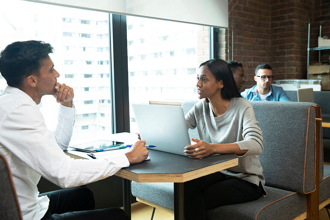 People with laptop meeting at booth in office cafeteria