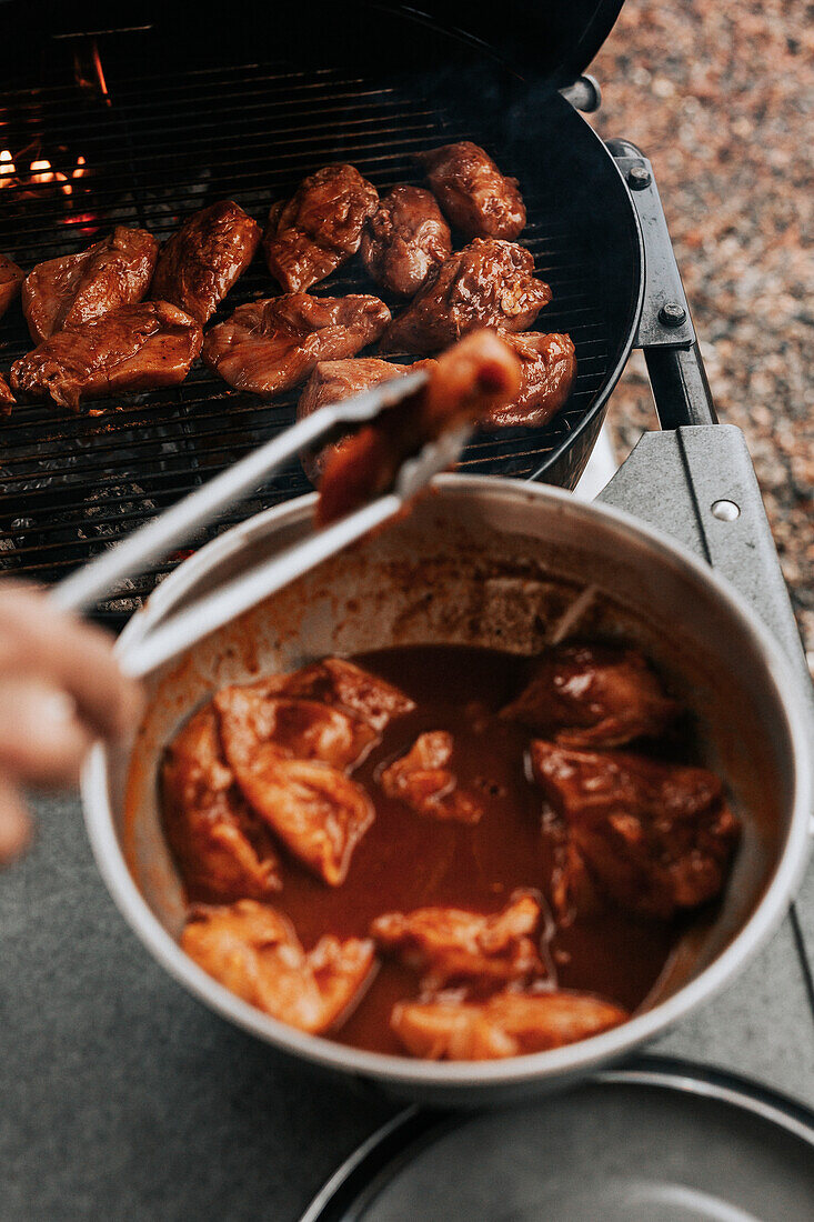 Putting marinated meat on barbecue