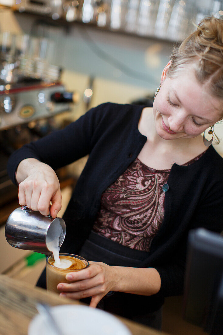 Weibliche Barista bereitet Cappuccino zu