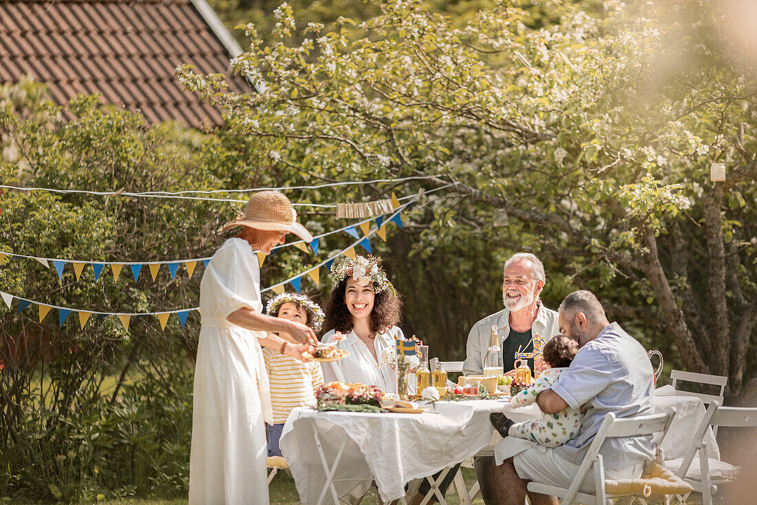 Familie feiert Mitsommerfest im Garten (Schweden)
