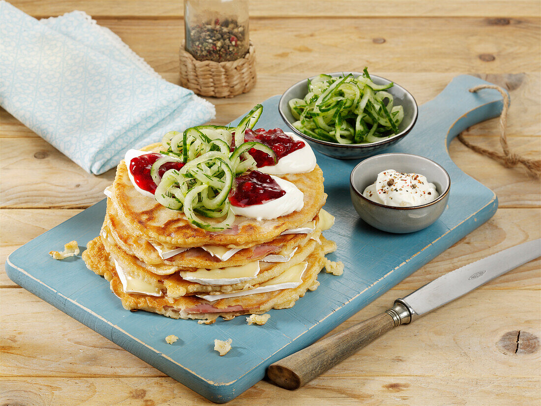 A stack of pancakes layered with Camembert, ham and cranberries