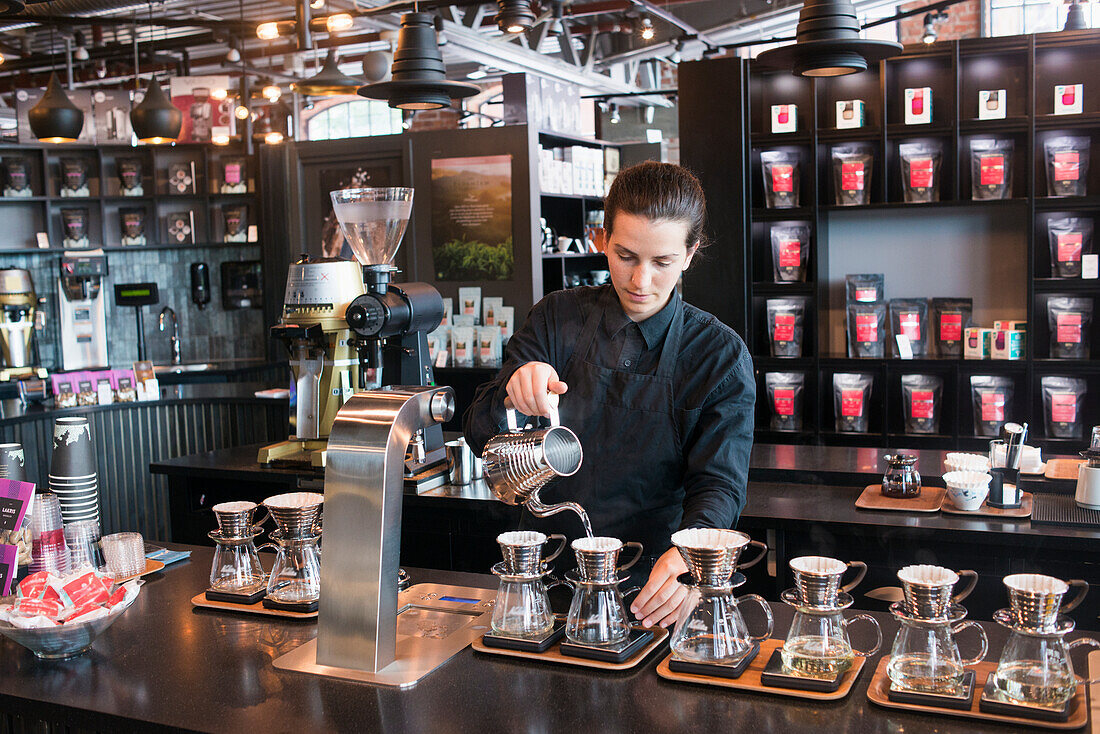 Weibliche Barista bereitet Kaffee an der Theke zu