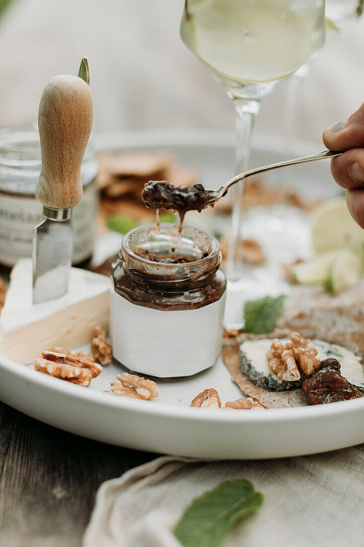 Hand hält Löffel mit Chutney über Glas