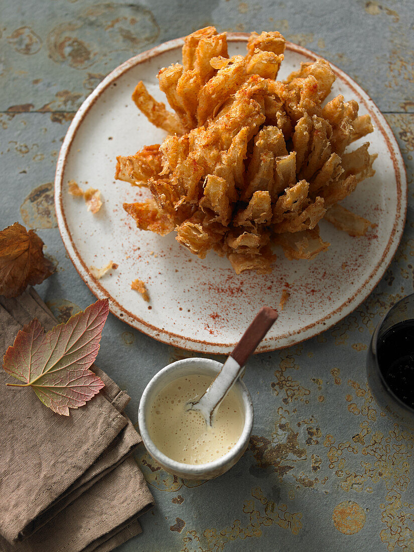 A baked onion flower with white BBQ sauce