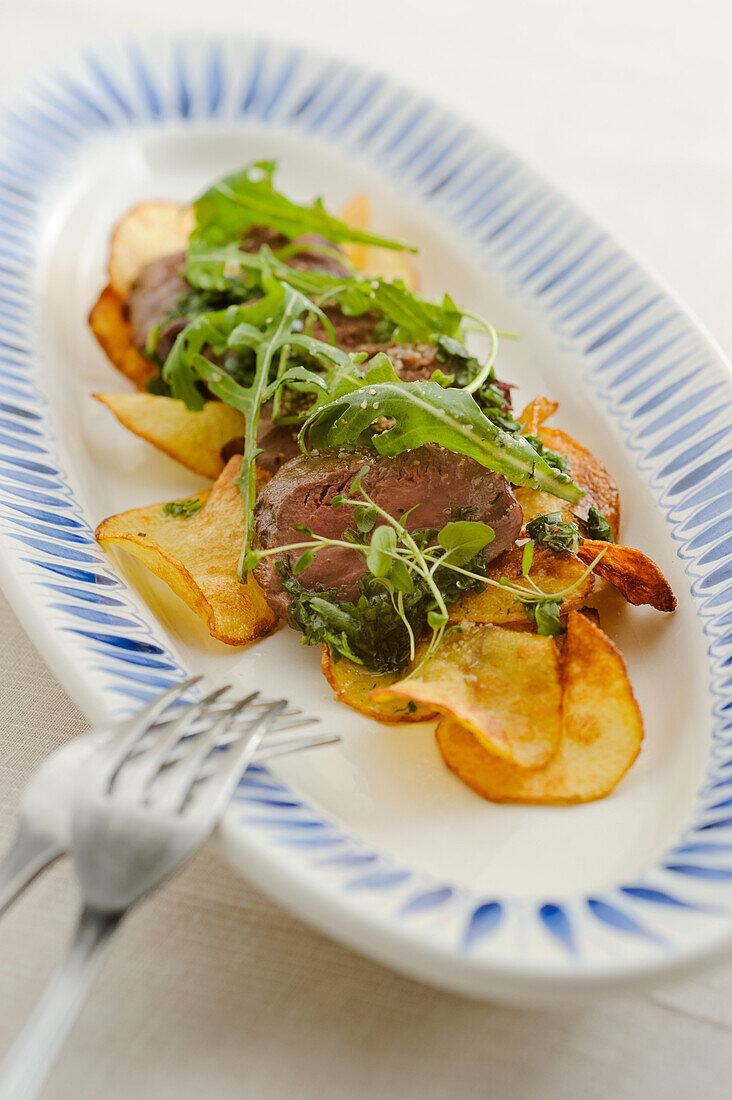 Rehmedaillons auf Kartoffelchips mit Rucola-Mohnsalat