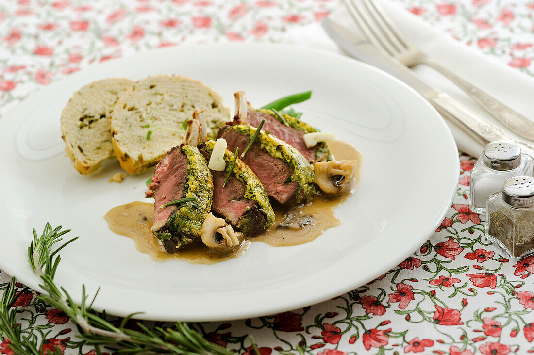 Poppy seed crusted saddle of lamb with slices of herbed bread and Duxelles mushroom sauce