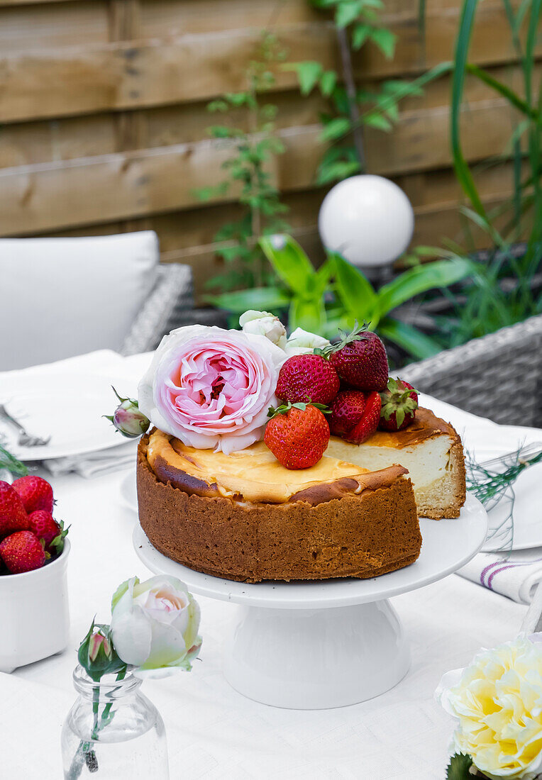 Cheesecake on a white cakestand on a table in a garden