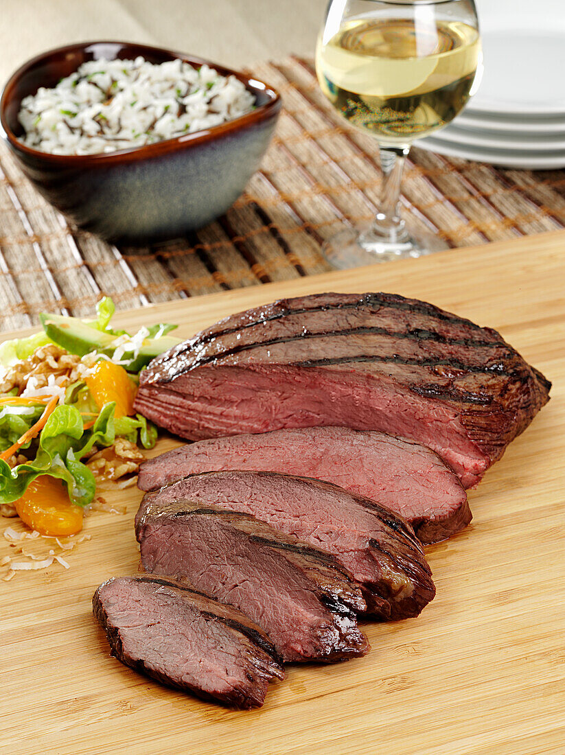 A medium rare beef Tri Tip roast on a cutting board with slices