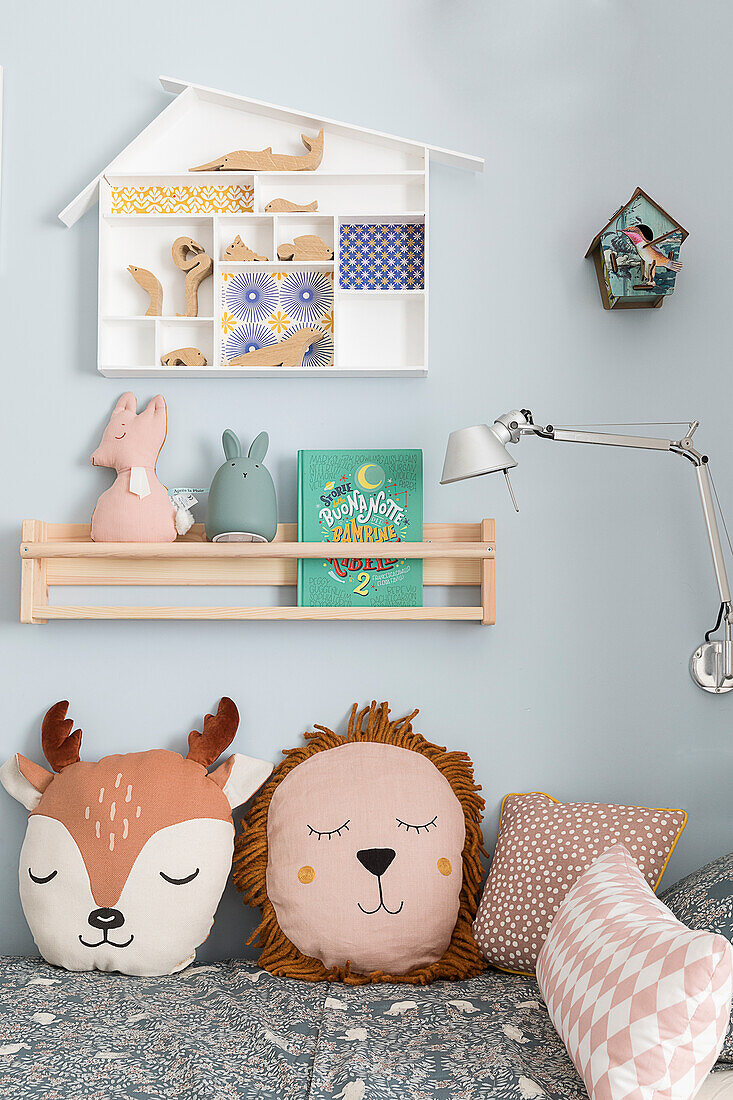 Bed with animal pillows, shelves above in children's room