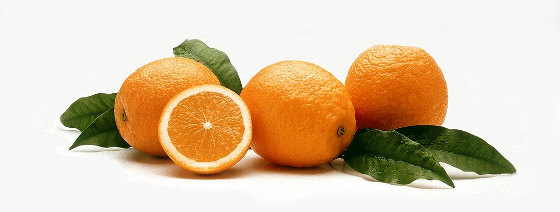 Drei ganze Orangen sowie eine Hälfte & Blätter