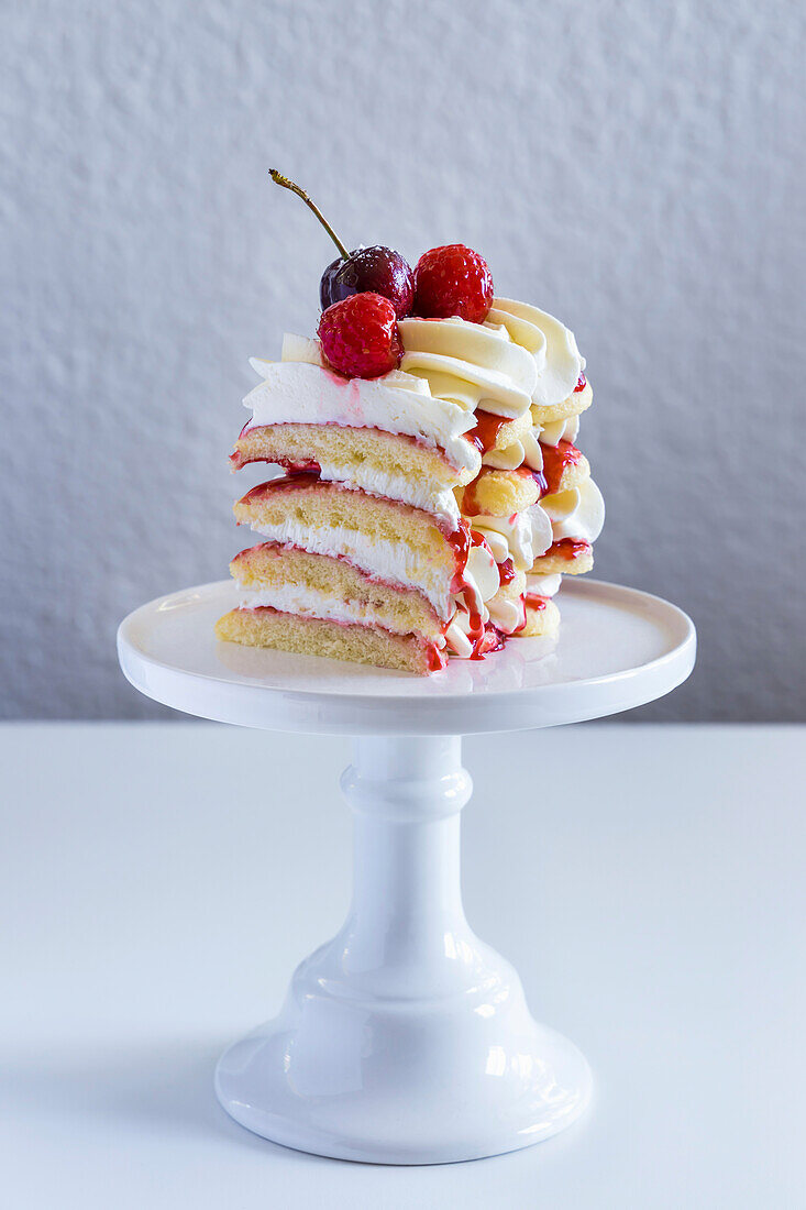 Raspberry tiramisu, layers of sponge, cream and fruit sauce, decorated with fresh raspberries and cherries