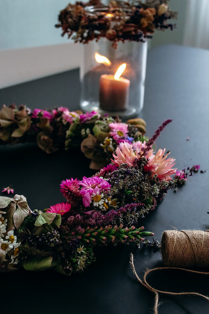 Sommerlicher DIY-Kranz, im Hintergrund Windlicht