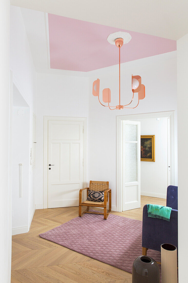 Designer armchair and lamp in the entrance area in a bright, renovated apartment in an old building