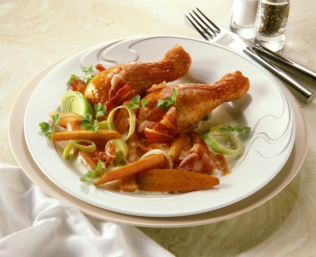 Hähnchenschenkel mit Möhren-Lauch-Gemüse & Bacon auf Teller