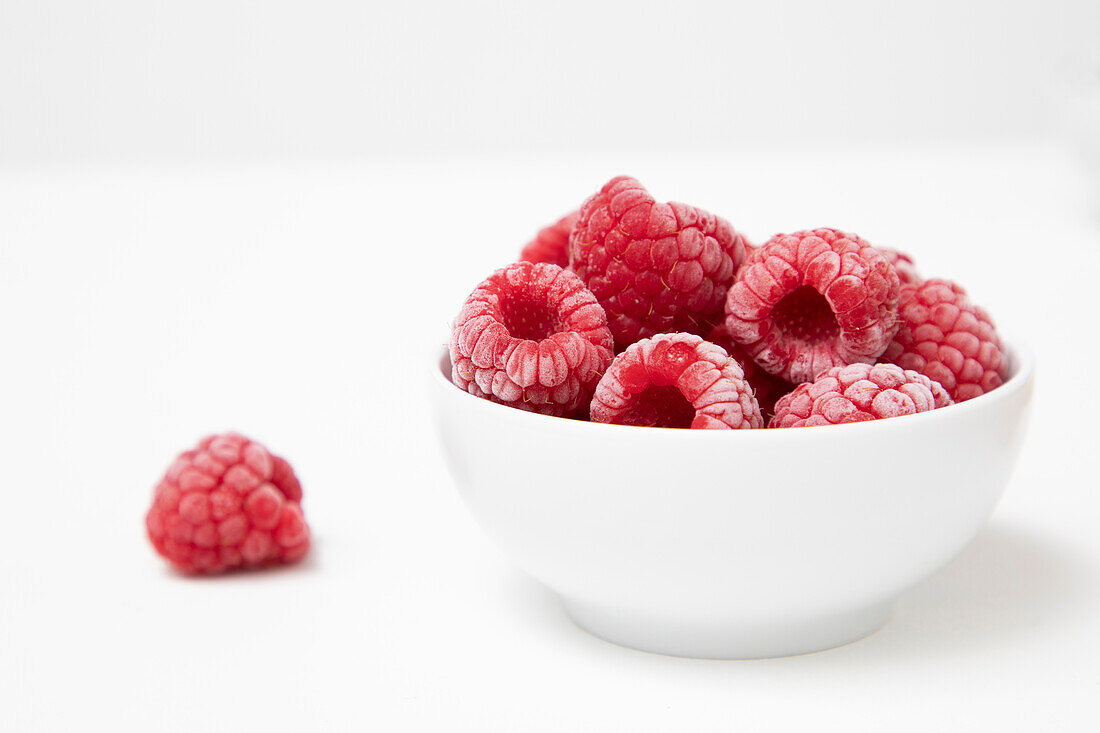 Frozen Raspberries in a white bowl on a white background