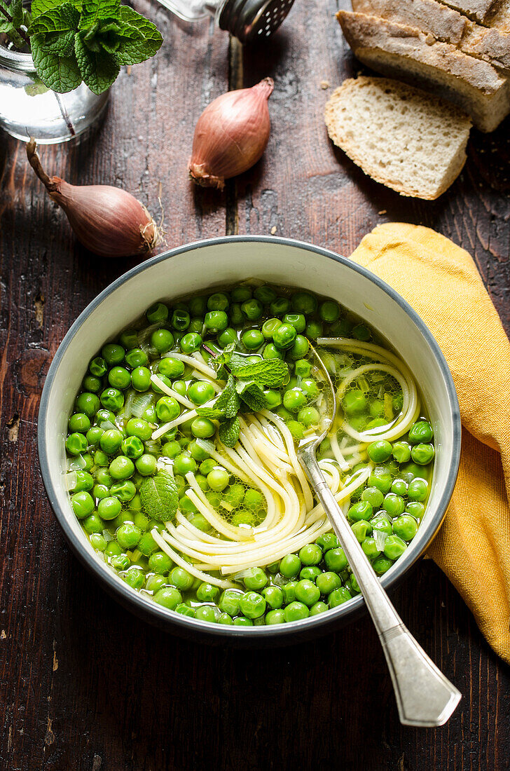 Pea Soup with Pasta in a white bowl on a wooden table