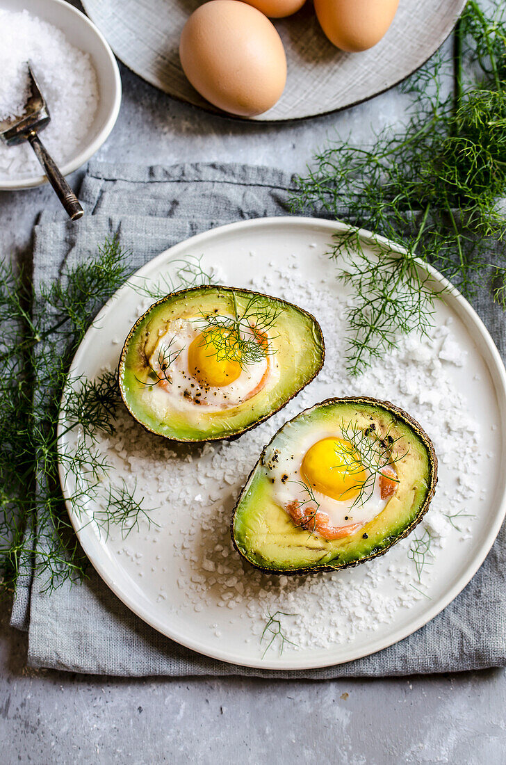 Stuffed avocado with egg and herbs on a white plate