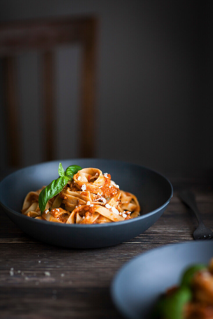 A blue bowl of pasta and tomato sauce on a table